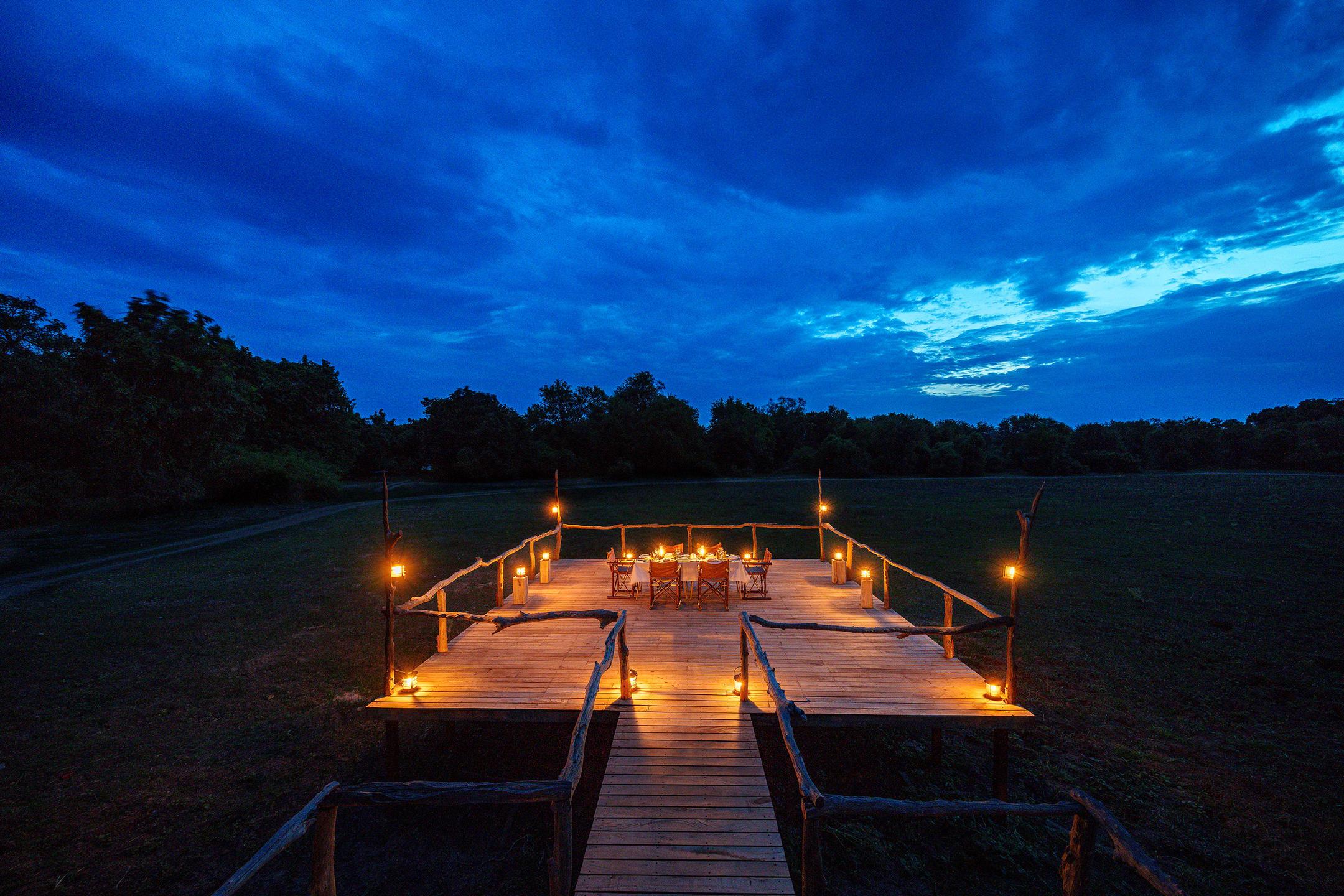 Candlelit dining on a safari deck at dusk