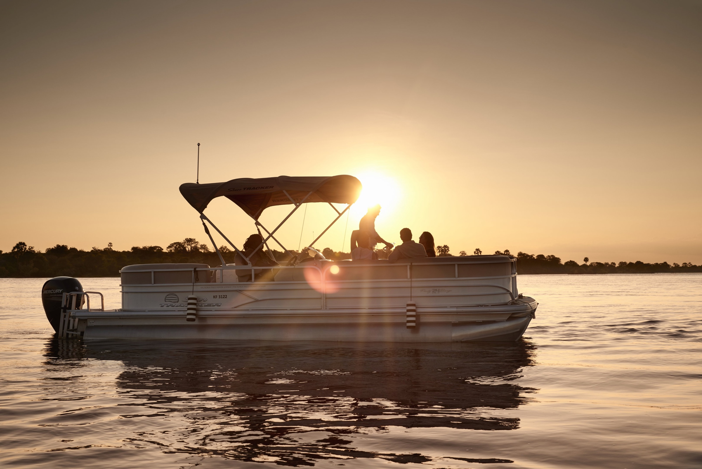 Guests cruising on a boat on the Zambezi River at sunset in Zimbabwe