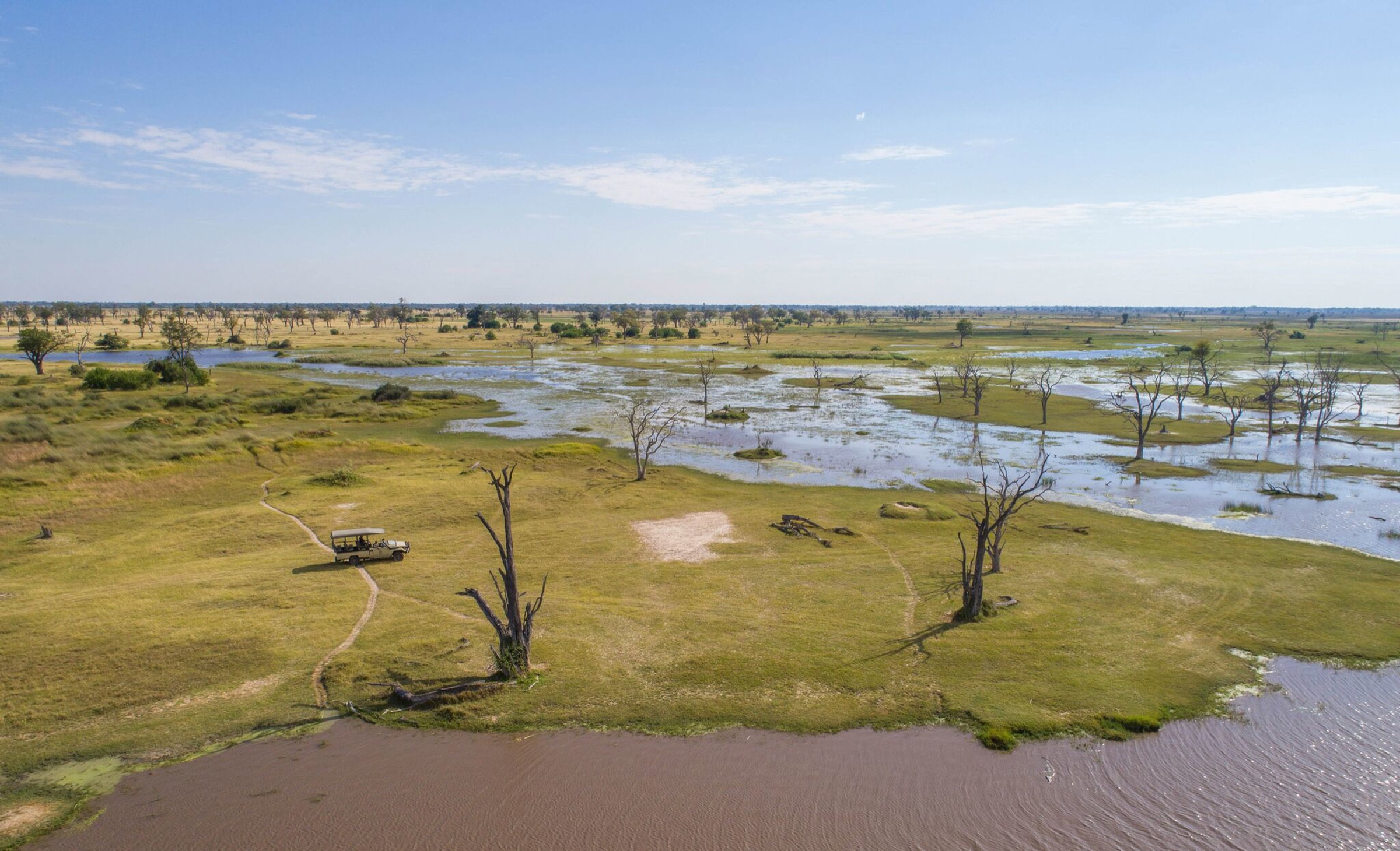 A safari vehicle crossing the floodplains of Botswana’s Okavango Delta.