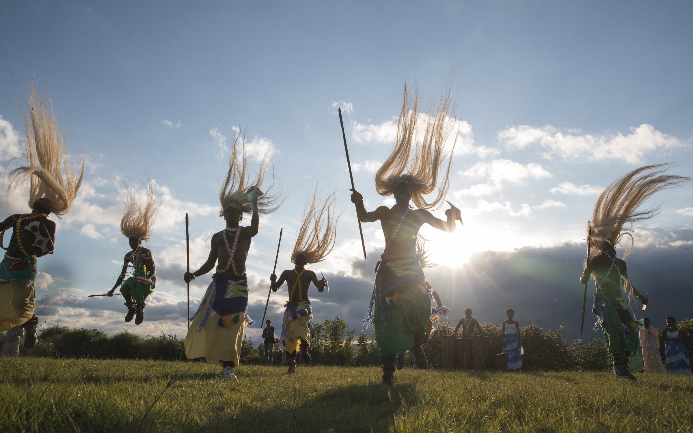 Dancers in colourful dress performing outdoors in Rwanda at sunset.