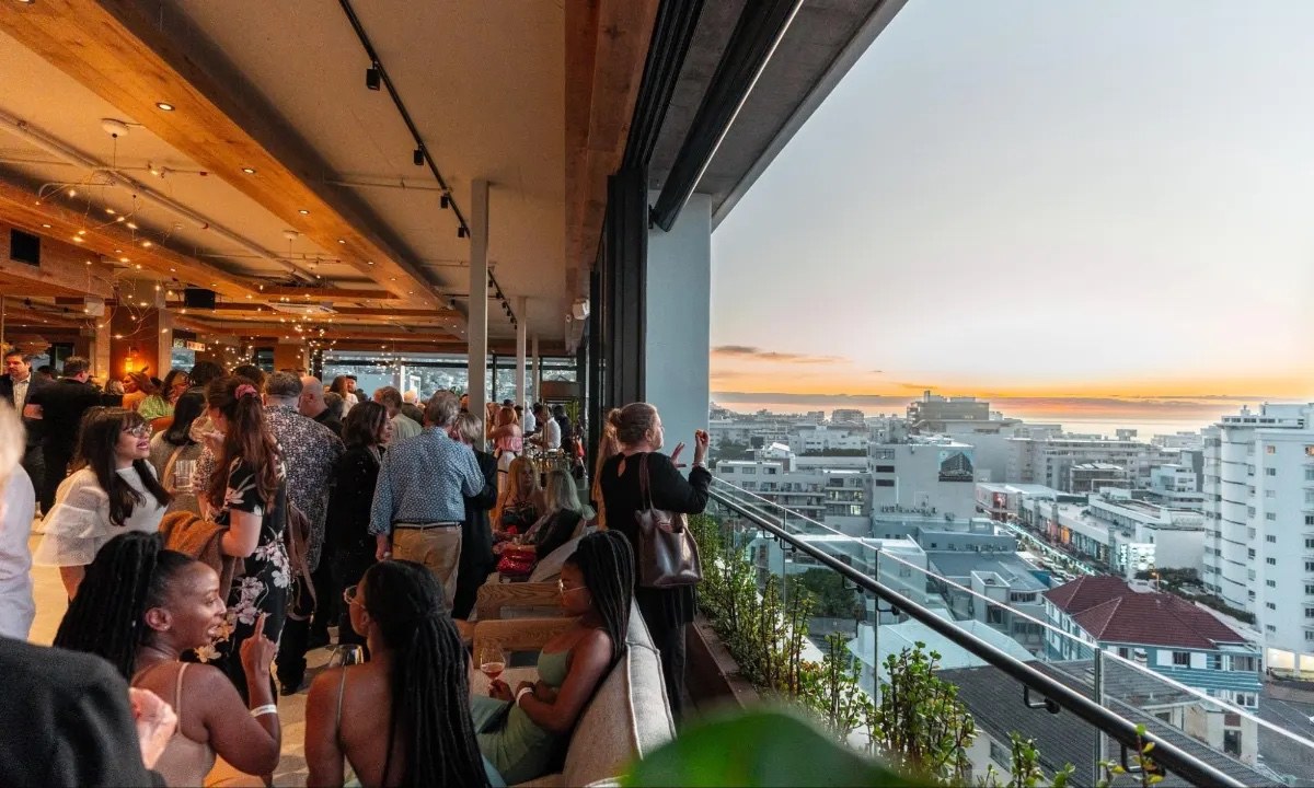 Guests gathering on a rooftop terrace overlooking Cape Town at sunset.