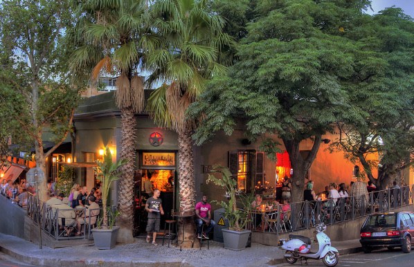 Guests on a restaurant terrace beneath trees in De Waterkant.
