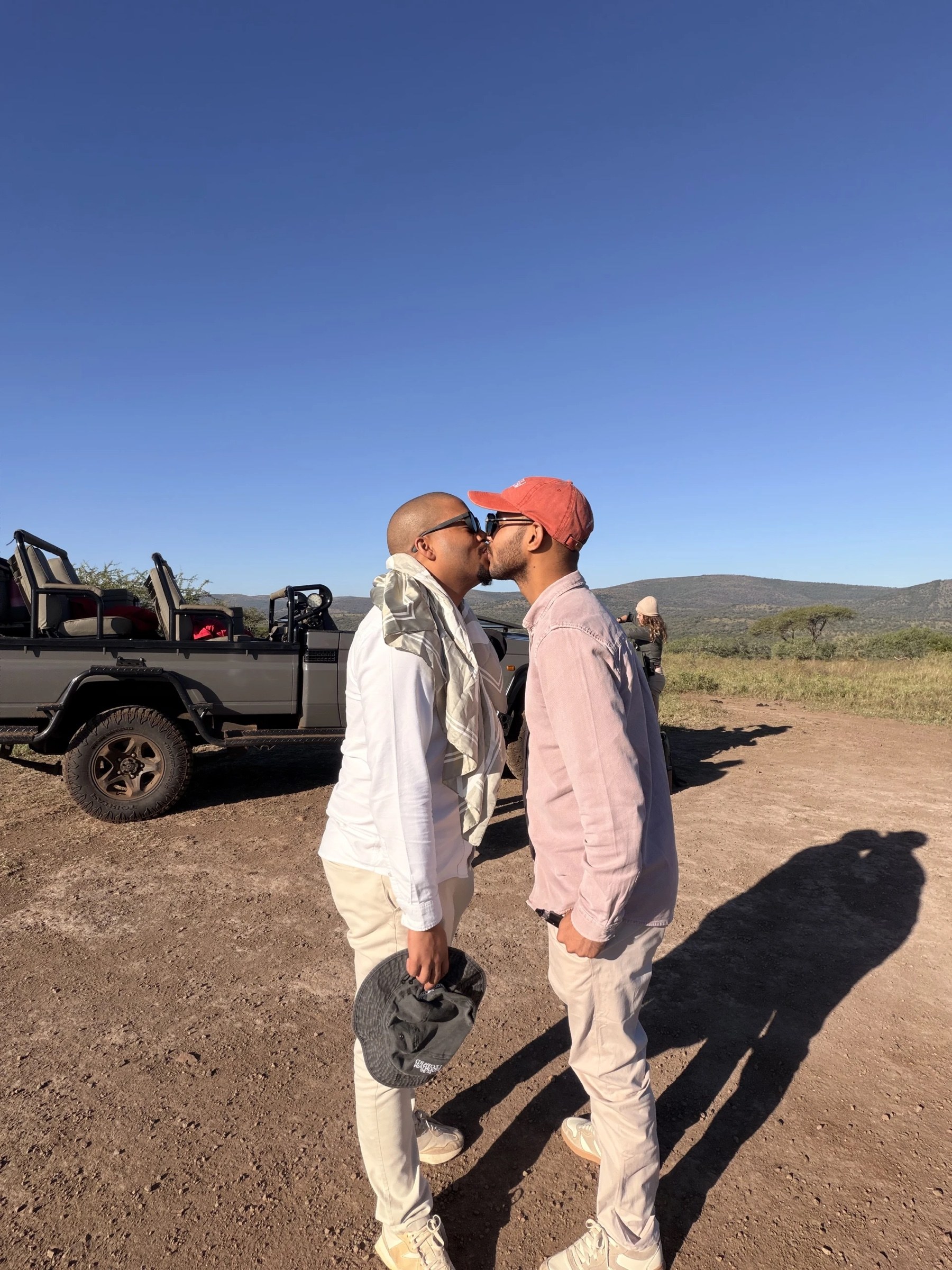 Zannon James and his partner kissing beside a safari vehicle.