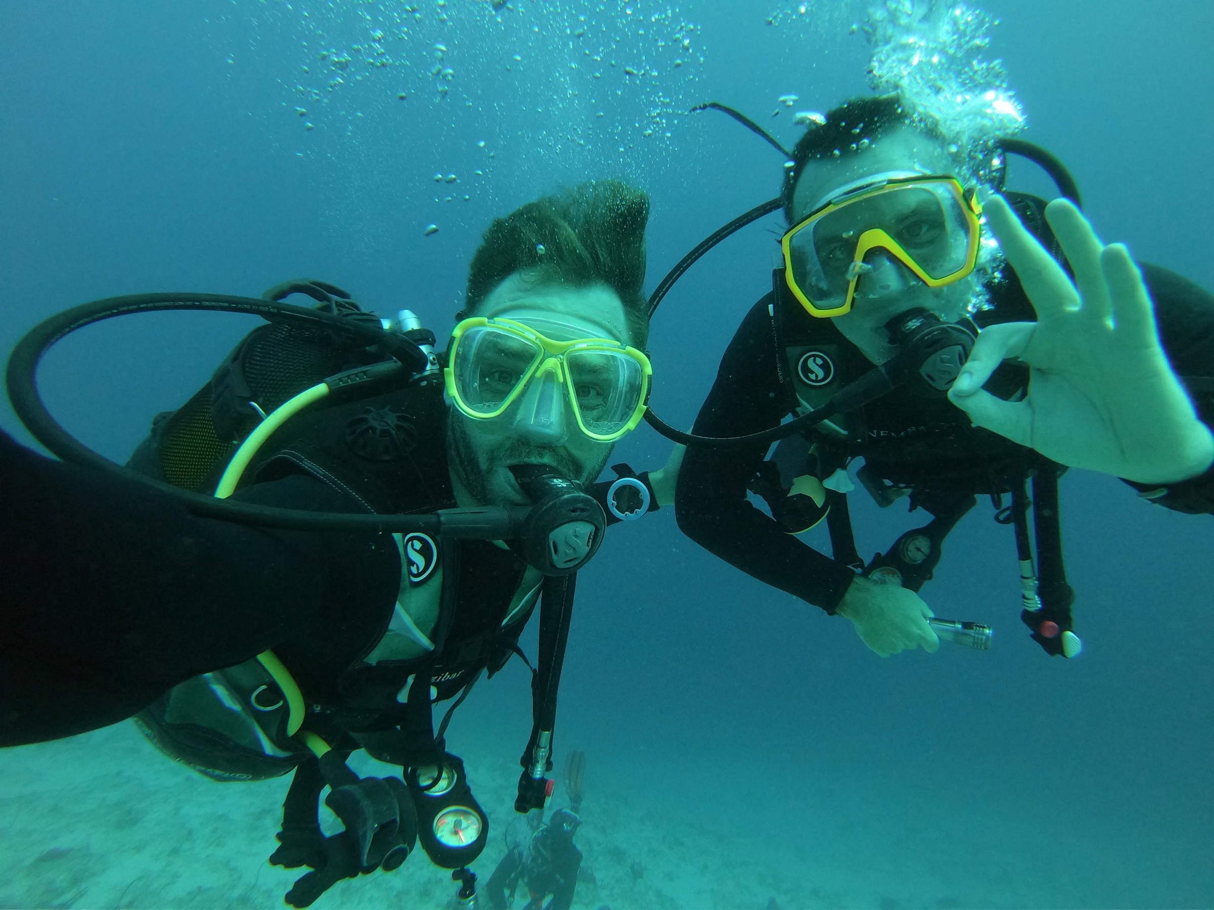 Two scuba divers wearing yellow masks underwater in Zanzibar.