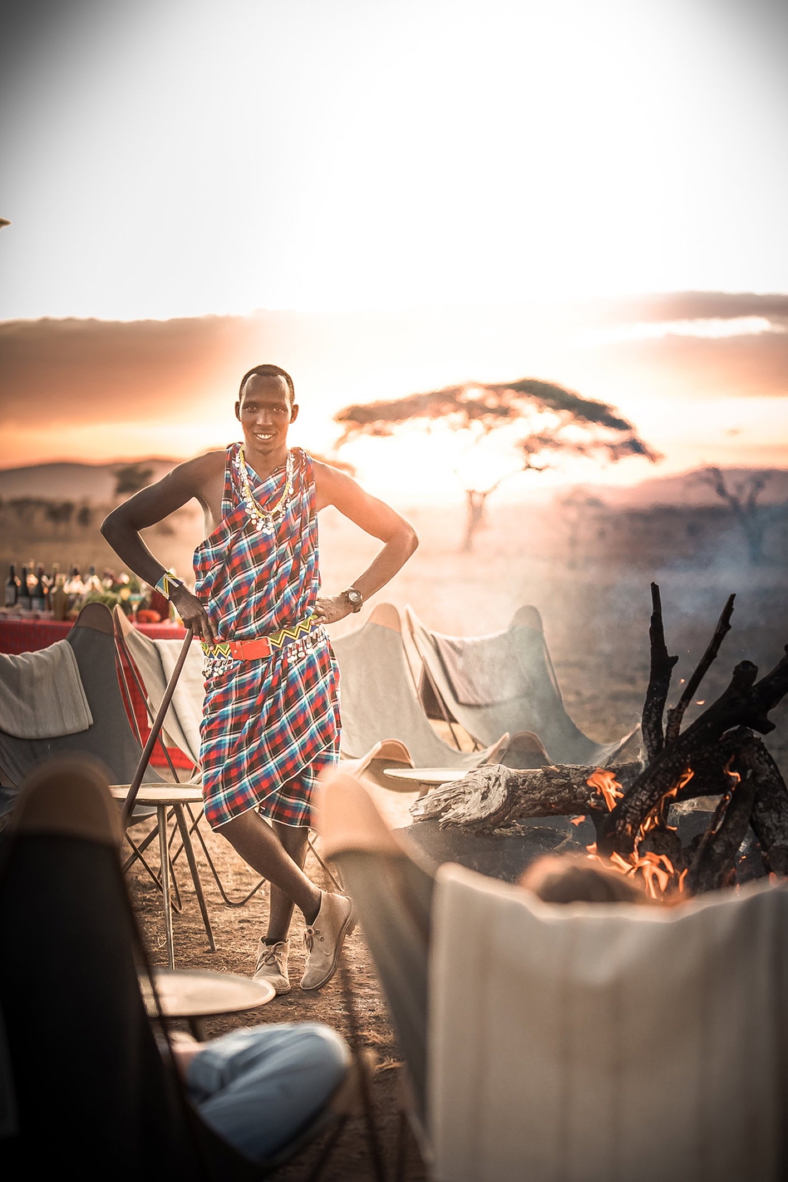 A Maasai host beside a campfire at sunset in Tanzania.