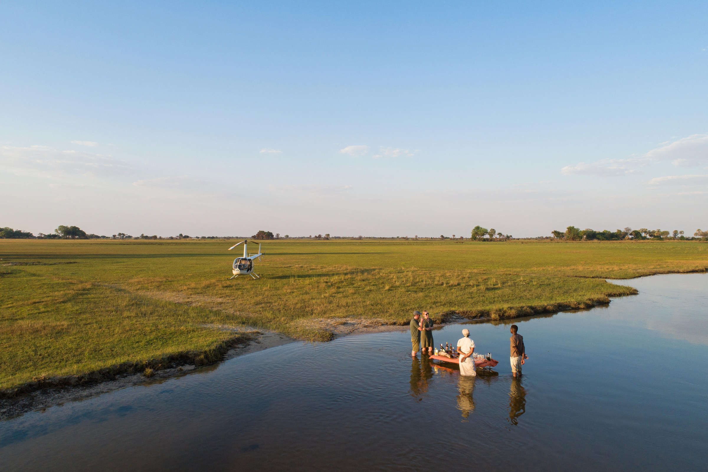 Helicopter and curated setup on Botswana salt pans at dusk